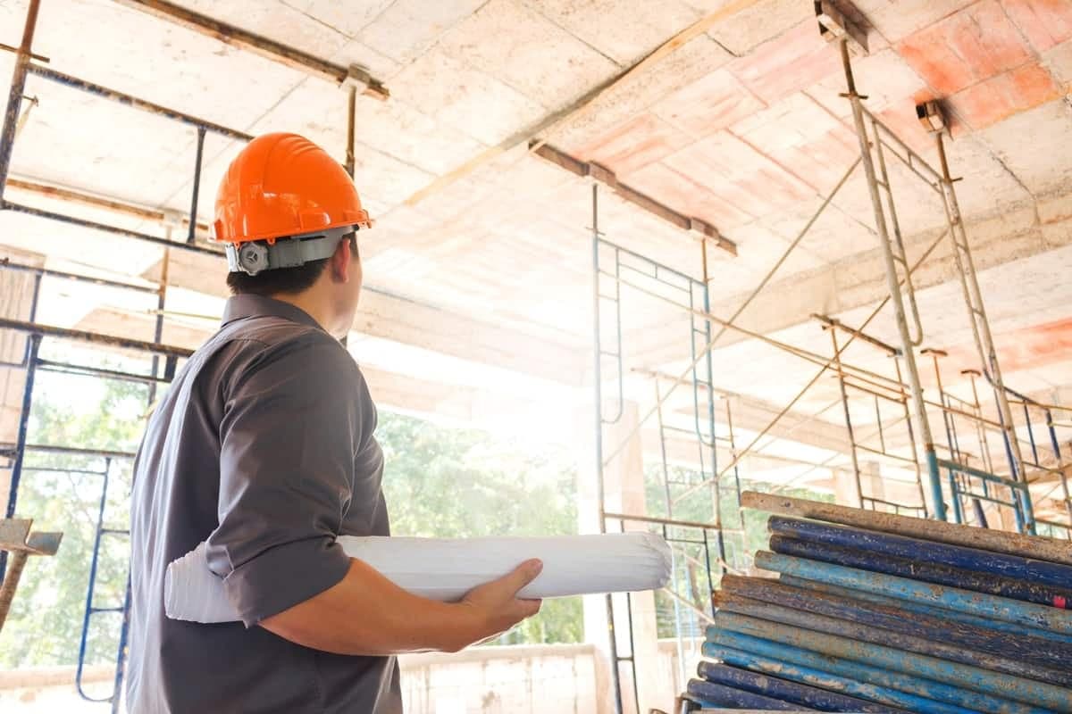 Bausachverständiger auf Baustelle mit Plan in der der Hand