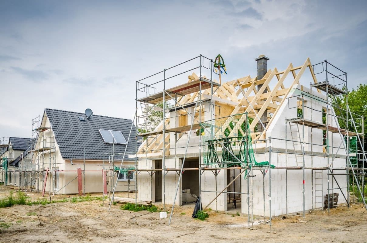 Ein Rohbau mit Gerüst. Der Bauherr erledigt viele Arbeiten in Eigenleistung. Durch die Muskelhypothek will er so Geld sparen.