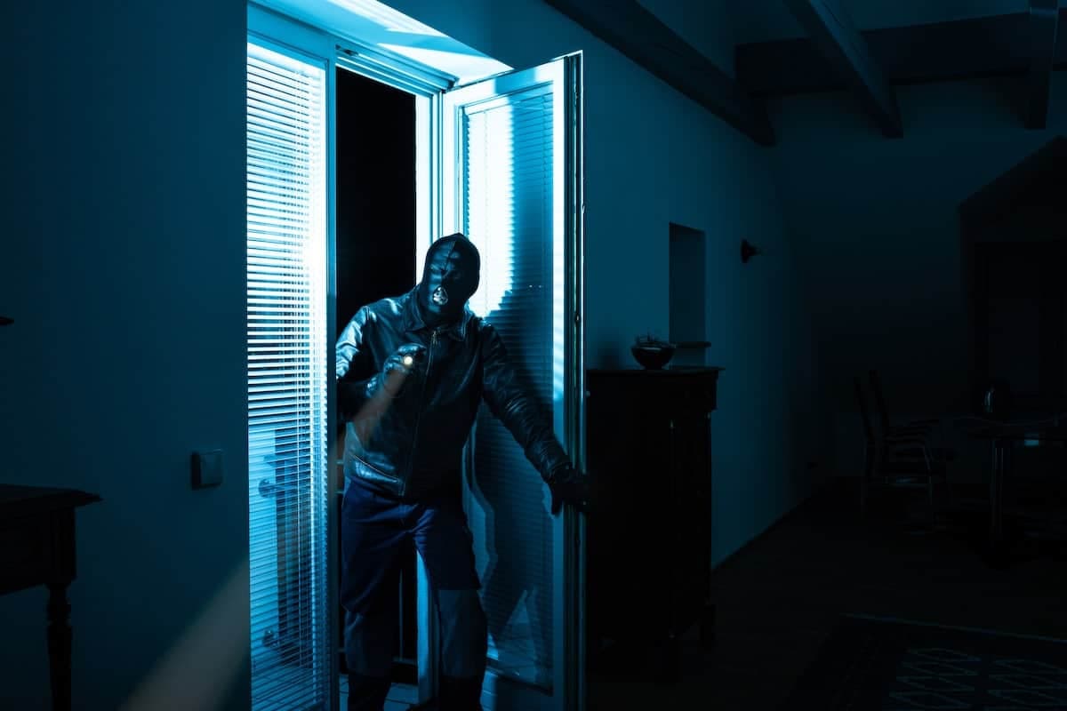 Ein Einbrecher bricht durch ein Fenster in ein Haus ein