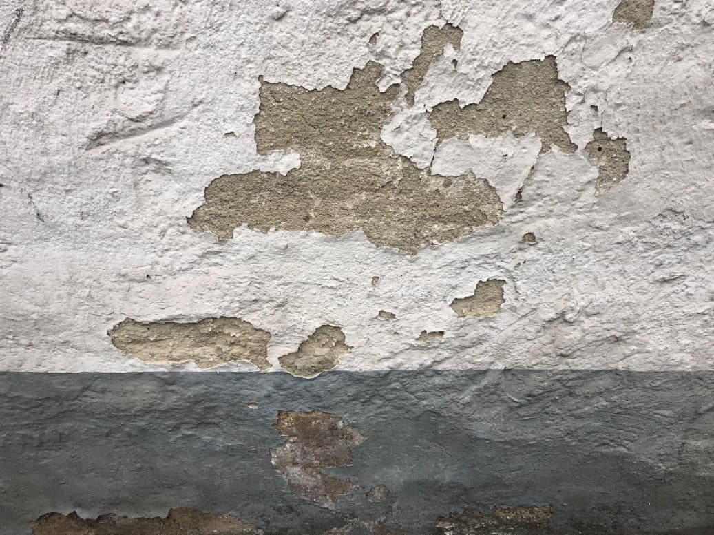 Eine alte Fassade mit ablösender Farbe und ablösendem Putz.
