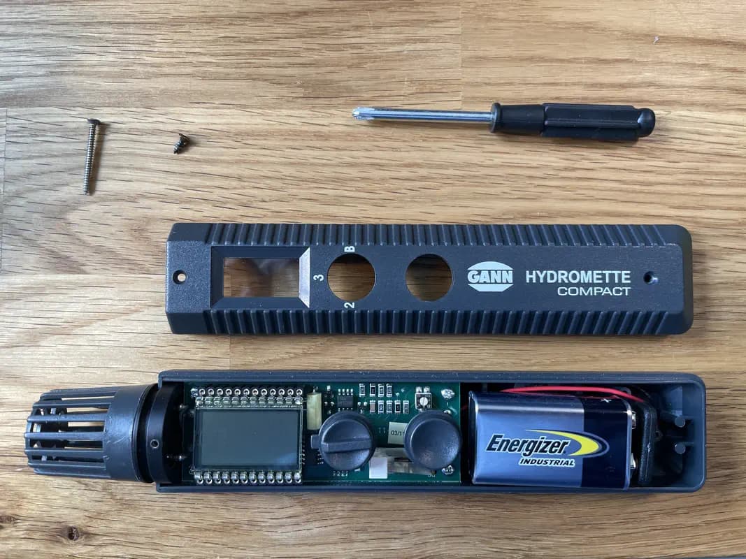 Das Holzfeuchtemessgerät GANN Hydromette Compact mit geöffnetem Batteriefach, das einen 9 V Block zeigt.