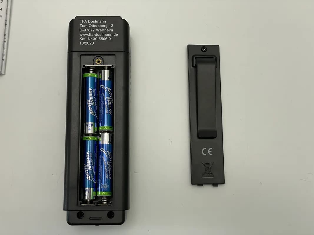 Das Holzfeuchtemessgerät TFA Feuchtemesser 30.5506 liegt mit aufgeschraubtem Batteriefach auf dem Tisch.