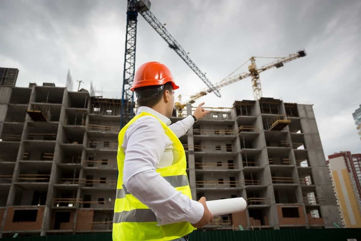 Bausachverständiger mit Helm, zeigt auf Rohbau während einer Qualitätskontrolle