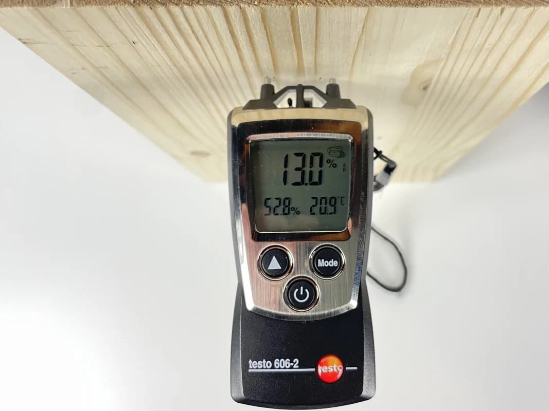 Mit dem Feuchtemessgerät testo 606-2 wird die Holzfeuchtigkeit quer zur Faser gemessen. Das Messgerät steckt in einem Stück Schnittholz und zeigt eine Holzfeuchtigkeit von 13,0 % an.