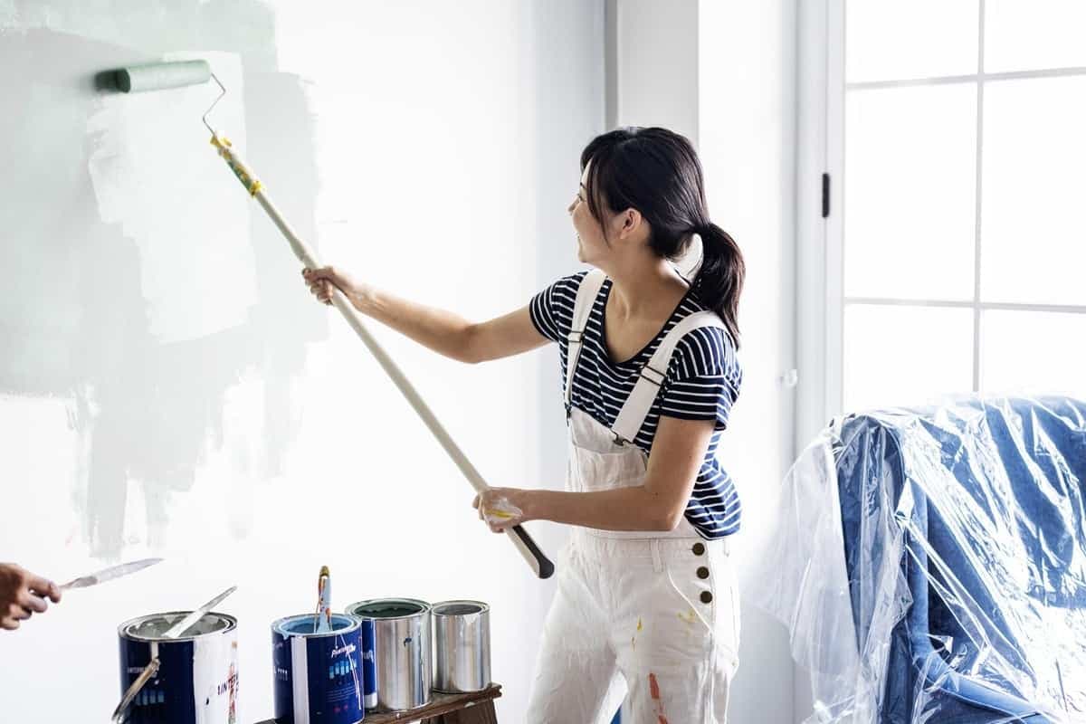 Frau streicht eine Wand selbst weiß