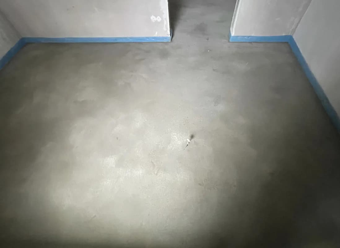 : Ein Innenraum mit Zementestrich und Randdämmstreifen. Es ist ein Neubau. Der Estrich trocknet schon ab.