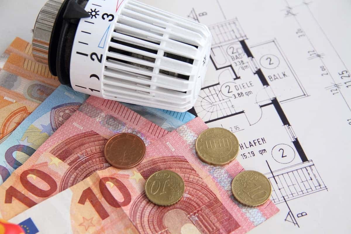 Heizungsthermostat mit Geldscheinen auf einem Bauplan