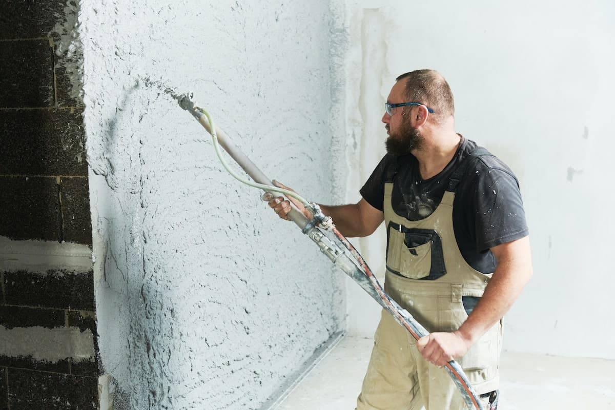 Ein Stuckateur, der Putzmörtel auf die Wand spritzt